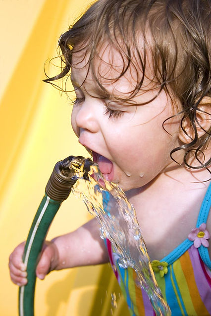 girl drinking water from a hose